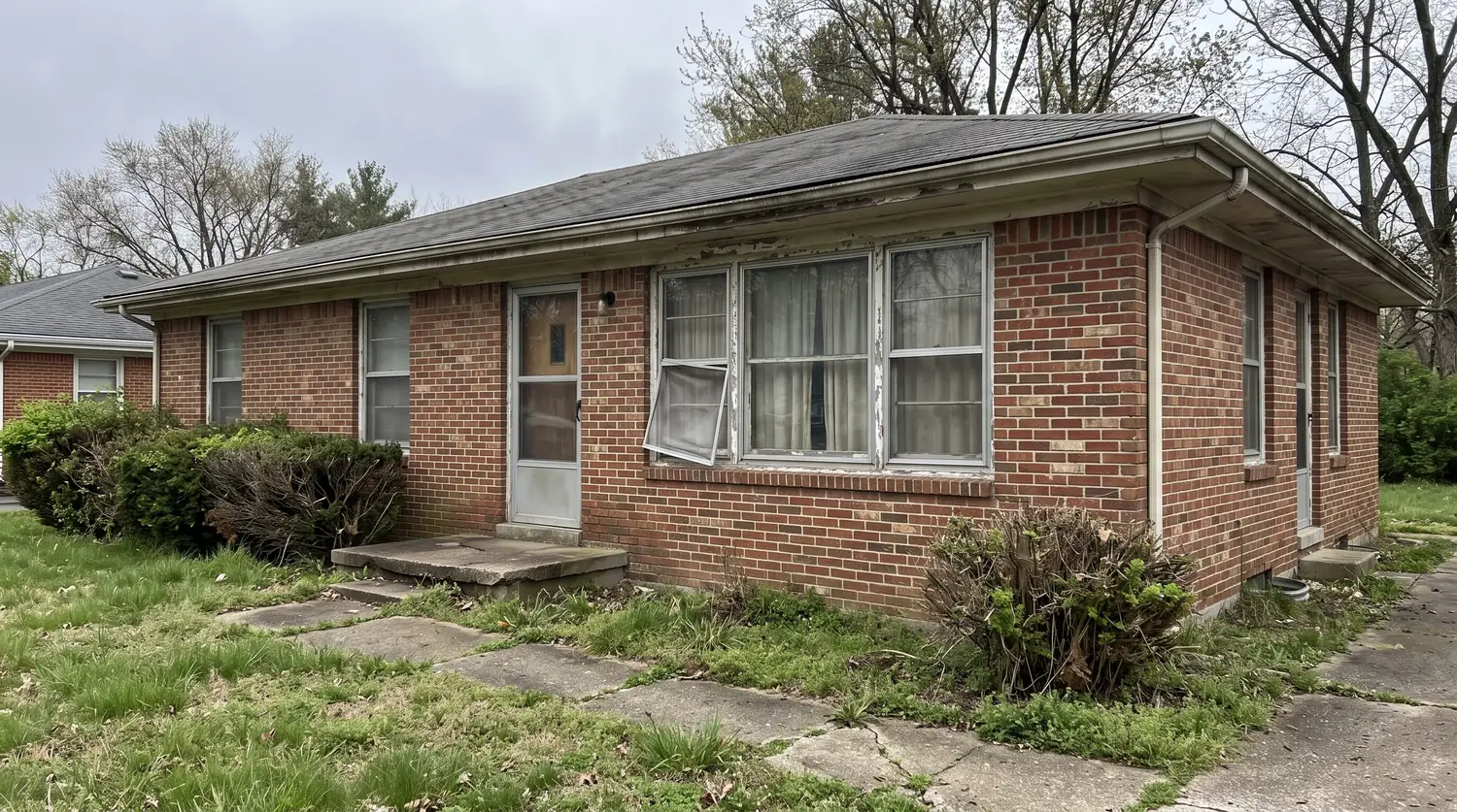 Before: A dated brick ranch house front with old single-pane silver aluminum windows with peeling frames and a sagging screen, flat gray lighting